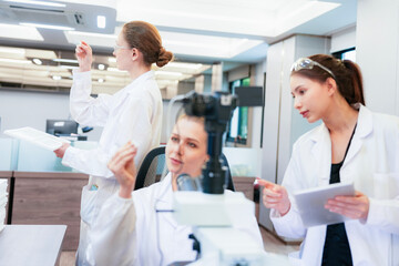 Fototapeta premium Diverse team of female scientists working in busy digital pathology lab. Researchers analyzing histology slides using microscope, tablet, and visual inspection for medical diagnosis.