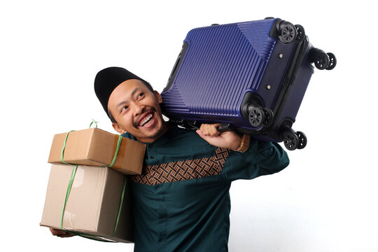 Asian Muslim man carrying a suitcase and a cardboard box, ready for mudik, the Indonesian homecoming tradition for Eid Mubarak. Isolated on a white background.