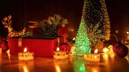 Red gift box and candlelight on a wooden table.