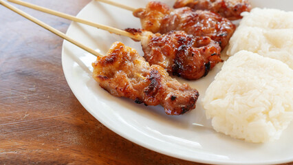 Sticky rice with grilled pork on a wooden table.