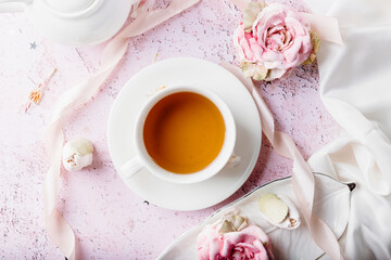 Tea cup on a pastel pink background with handcrafted zephyr and marshmallow and light fabric. Simple flat lay with copy space.