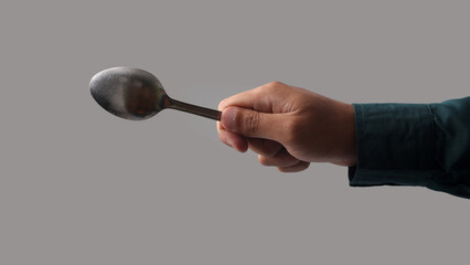 Close-up of a human hand holding a spoon, isolated on a white background. Suitable for concepts of...