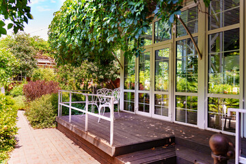 Sunny garden view with a sitting area by the glass house