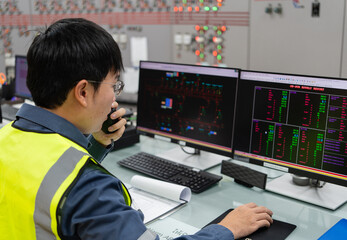 Electrical engineer making operational decisions while using radio communication and reviewing system data on control screens inside power facility, ensuring secure command flow and stable electricity