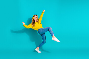 Young woman dancing in a yellow sweater against a blue background joyful and stylish moment