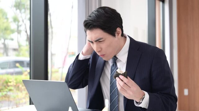 会社の休憩中に時間がなくてオニギリなどを急いでオフィスで食べる忙しい男性のビジネスシーン動画