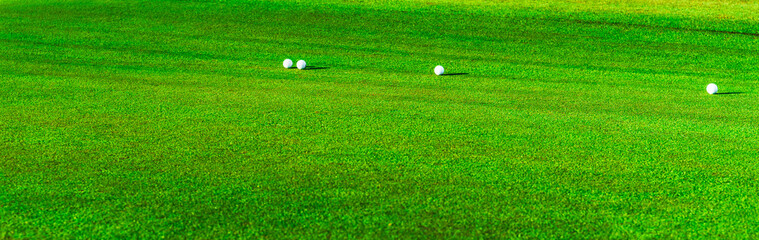 Golf balls on a lush green course during a sunny day in a luxury resort setting