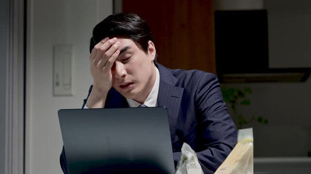 暗いオフィスで仕事が終わらず残業でパソコンの前で困る悩むや叫ぶのポーズのビジネスマン 頭を抱える動画　ご飯食べる暇な～い