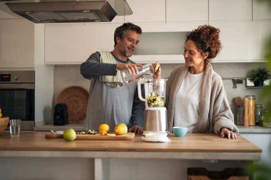 Couple Sharing Healthy Breakfast as They Make a Fresh Fruit Smoothie in a Modern Cozy Kitchen - Powered by Adobe