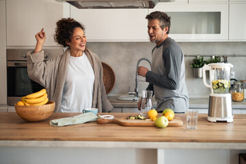 Happy Couple Enjoys Smoothie Time in Modern Kitchen, Sharing Laughs and Fresh Fruit Together Today