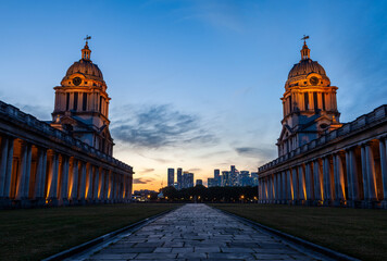 Old Royal Naval College in Greenwich, London at sunset with city skyline in the background.