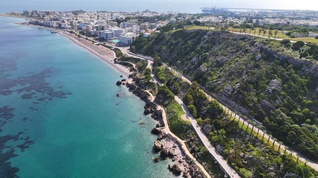 Aerial drone cinematic video of beautiful beach with wonderful seaside promenade of Kato Petres featuring Cave Archangel Michael Panormitis, Rhodes island, Dodecanese, Greece