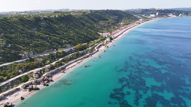 Aerial drone cinematic video of beautiful beach with wonderful seaside promenade of Kato Petres featuring Cave Archangel Michael Panormitis, Rhodes island, Dodecanese, Greece