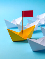 Yellow Paper Boat with Red Flag Leading White Boats on Blue Background
