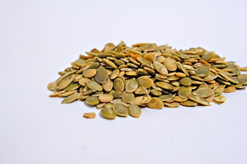 Pile of raw pumpkin seed on a white surface, snack food with healthy eating concept for ingredient, superfood, or agricultural product.