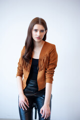 Professional fashion model wearing brown jacket and black outfit posing in studio on clean background, elegant young woman portrait for modeling agency portfolio, modern commercial beauty photography