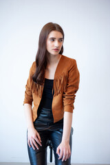 Professional fashion model wearing brown jacket and black outfit posing in studio on clean background, elegant young woman portrait for modeling agency portfolio, modern commercial beauty photography