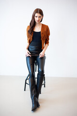 Professional fashion model wearing brown jacket and black outfit posing in studio on clean background, elegant young woman portrait for modeling agency portfolio, modern commercial beauty photography