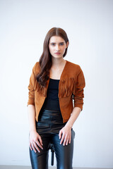 Professional fashion model wearing brown jacket and black outfit posing in studio on clean background, elegant young woman portrait for modeling agency portfolio, modern commercial beauty photography