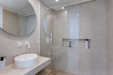 Modern minimalist bathroom with round mirror, walk-in shower and white ceramic washbasin