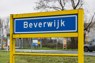 Blue and yellow Dutch place name sign welcoming visitors to the municipality of Beverwijk with an industrial background.