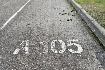 Obraz premium Parking Surface Decay, Cracked Lot With Moss Growth, Weathered Pavement Showing Cracks And Moss Patches, Deteriorated Asphalt With Faded Markings And Moss Covering Surface