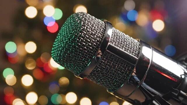 Extremely slow motion tracking shot orbiting a condenser microphone while festive colored Christmas tree illumination reflects gently off the polished equipment surface pro, broll, commercial