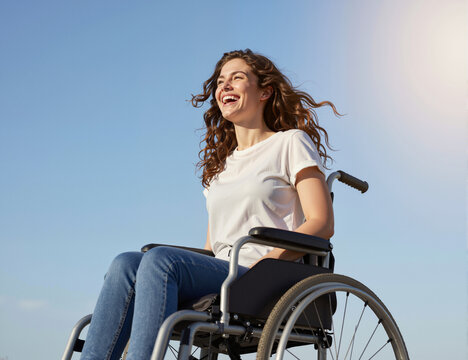 A smiling woman in a wheelchair enjoys a sunny day outdoors with a clear blue sky in the background representing joy, freedom, and empowerment in her life despite challenges
