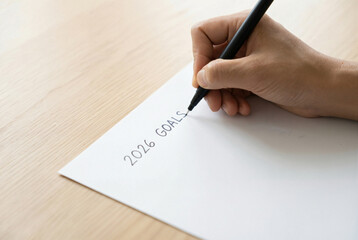Hand writing 2026 goals on paper with planning and resolution motivation