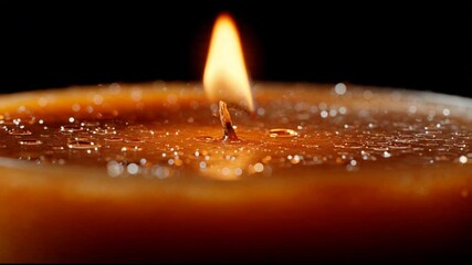Golden candle flame close up against dark background