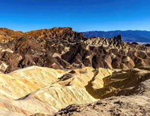 Eroded desert landscape with mountains under bright sky