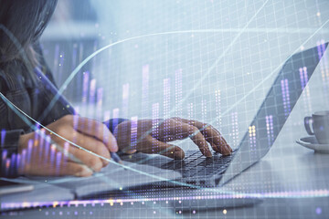 Double exposure of businesswoman hands typing on computer and forex graph hologram drawing. Financial analysis concept.