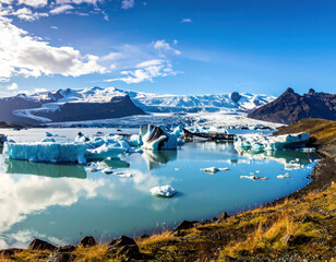 View of icebergs and glacier under blue sky in Iceland during the day with calm water and mountains in the background
