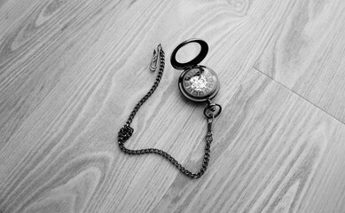 Vintage brown pocket watch with chain lying on wooden table, open cover antique mechanical...