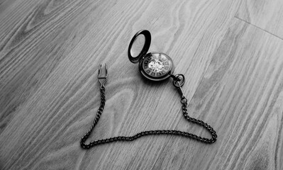 Vintage brown pocket watch with chain lying on wooden table, open cover antique mechanical...