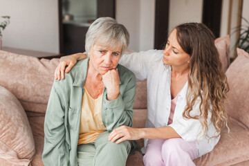 Grown up daughter soothe aged mother holds her hand feel empathy give her moral support, sad...