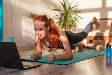 Young woman training by laptop video at home