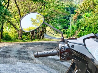 Left motorcycle handlebars, mirror, headlight switch, horn switch, and motorcycle signs light switch on the avenue tree road,