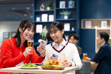 女子会でスマホを見る若い女性