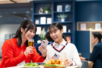 女子会でスマホを見る若い女性