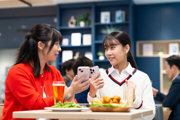 女子会でスマホを見る若い女性