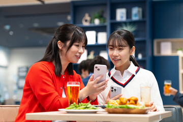 女子会でスマホを見る若い女性