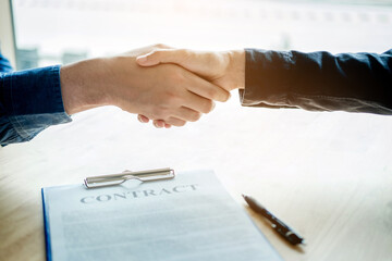 Business people negotiating a contract handshake between two colleagues
