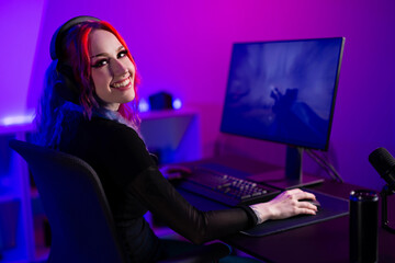 Young female gamer enjoying video games in a neon-lit streaming setup
