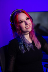 Young woman gaming with colorful hair and headset in vibrant lighting setup
