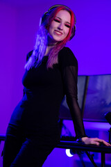 Young female gamer streaming with vibrant lighting and headphones