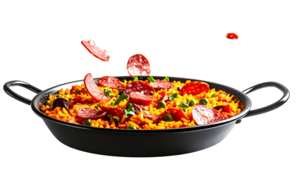 Vibrant paella dish in a black pan, ingredients like sausage falling from above