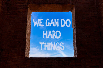 Obraz premium Support, help we can do hard things symbol. Concept words We can do hard things on beautiful window in ancient brick wall. Beautiful sky background. Business we can do hard things concept. Copy space.