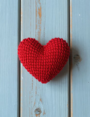Red knitted heart on light blue wooden wall
