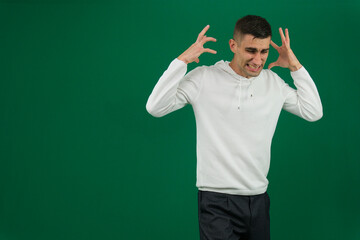 Young man stands against a beige background, looking perplexed with his hand raised, showcasing a mix of confusion and frustration. His casual attire adds to the relaxed atmosphere. High quality